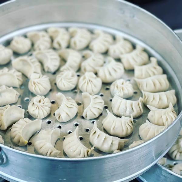 Freshly prepared Nepali momo dumplings steaming in a large metal steamer at Momo House San Antonio.