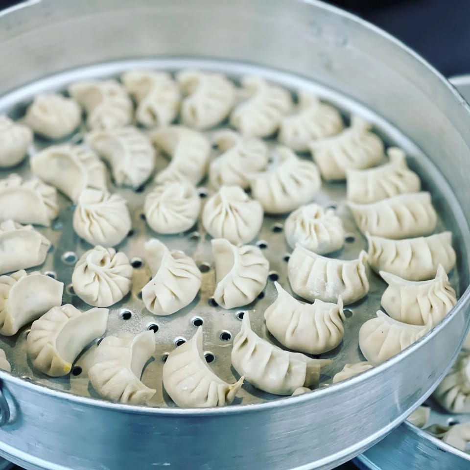Freshly prepared Nepali momo dumplings steaming in a large metal steamer at Momo House San Antonio.